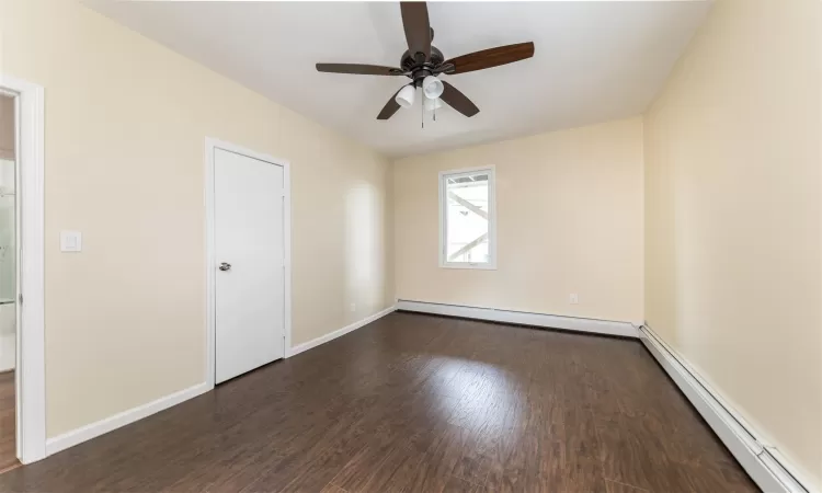 Unfurnished room featuring dark hardwood / wood-style floors, ceiling fan, and a baseboard heating unit