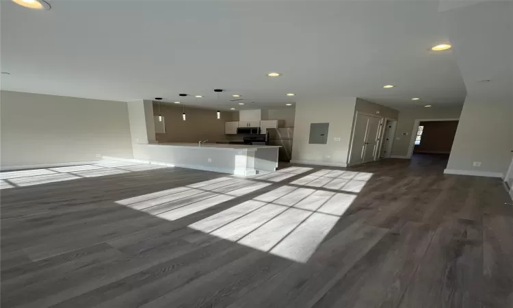 Unfurnished living room featuring electric panel, sink, and dark wood-type flooring