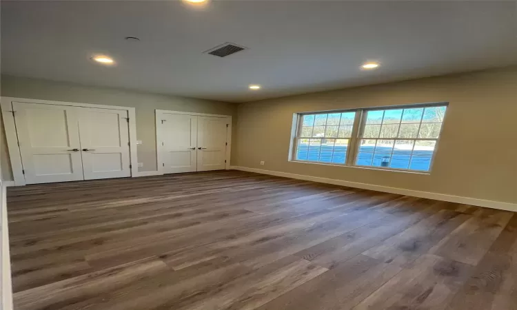 Unfurnished bedroom with two closets and dark wood-type flooring