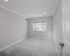 Empty room with an AC wall unit, light colored carpet, and ornamental molding