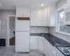 Kitchen featuring white cabinetry, sink, dark stone counters, white appliances, and decorative backsplash