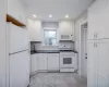 Kitchen featuring decorative backsplash, white appliances, white cabinetry, and sink