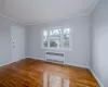 Living room featuring radiator heating unit, light hardwood / wood-style flooring, and ornamental molding