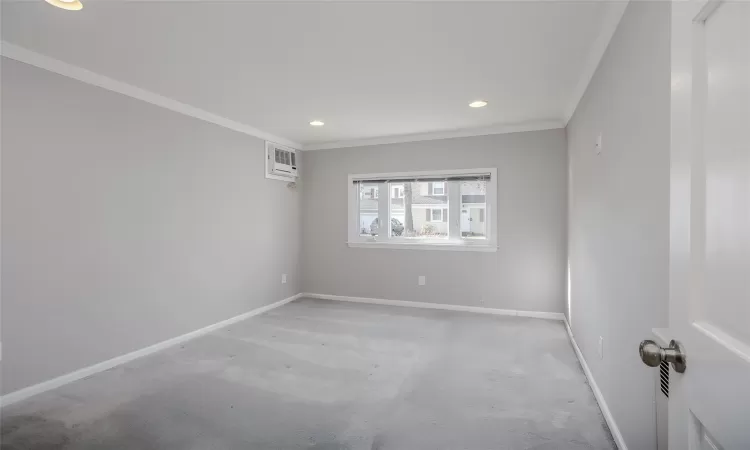 Carpeted spare room featuring a wall unit AC and crown molding