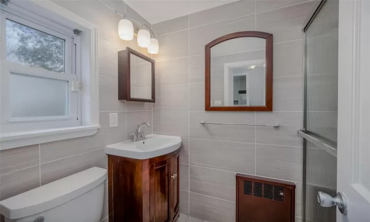 Bathroom with vanity, toilet, tile walls, and heating unit