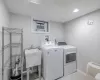 Clothes washing area featuring a wall mounted air conditioner, light tile patterned floors, washing machine and dryer, and sink