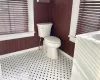 Bathroom with tile patterned floors, wood walls, and toilet