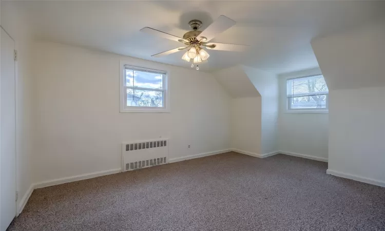 Bonus room with carpet, a wealth of natural light, radiator, and ceiling fan