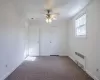 Unfurnished bedroom with carpet, radiator heating unit, and ceiling fan