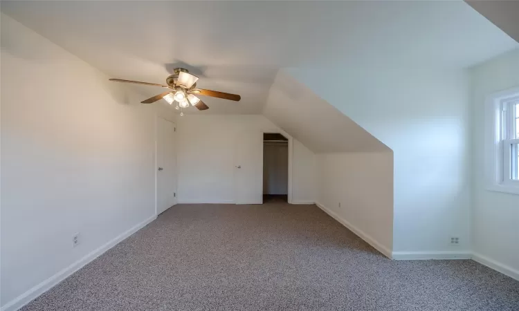 Additional living space with ceiling fan, light carpet, and vaulted ceiling