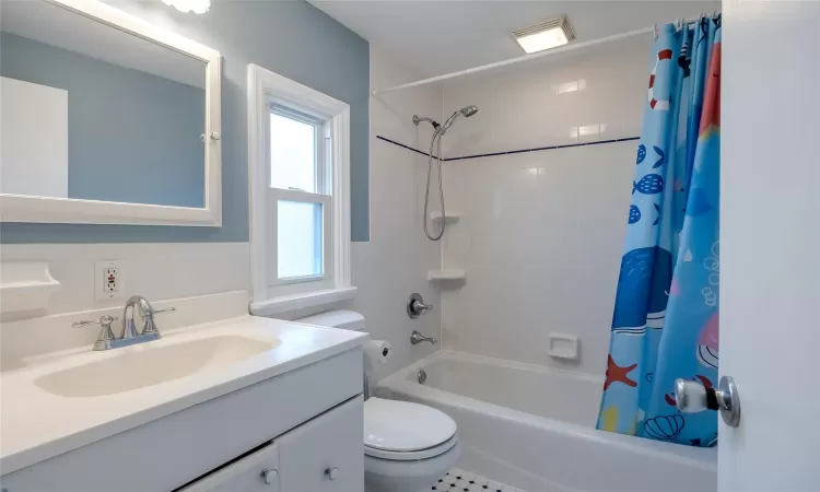 Full bathroom featuring vanity, toilet, a wealth of natural light, and shower / bath combo with shower curtain