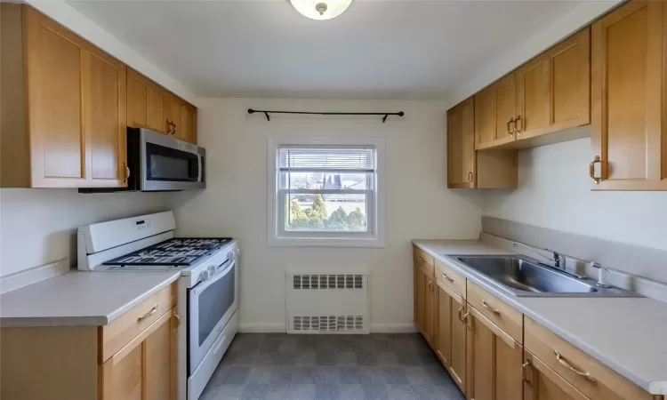 Kitchen featuring radiator, sink, and white gas range oven