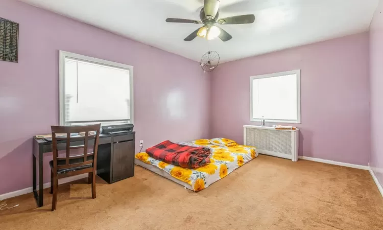 Carpeted bedroom with ceiling fan and radiator heating unit