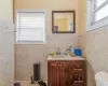 Bathroom with radiator heating unit, vanity, toilet, and tile walls