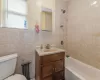 Full bathroom with vanity, toilet, tile walls, and tiled shower / bath combo