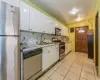 Kitchen with decorative backsplash, appliances with stainless steel finishes, sink, light tile patterned floors, and white cabinetry