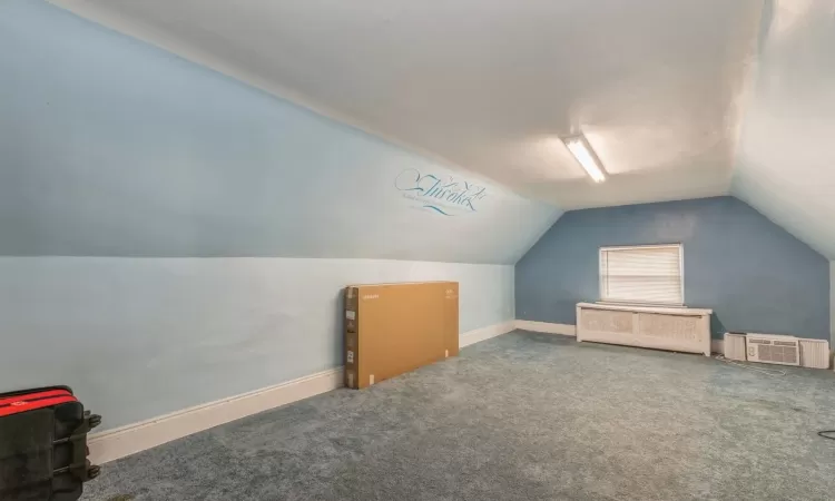 Bonus room with a wall mounted air conditioner, carpet floors, and lofted ceiling