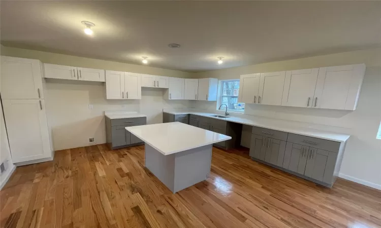 Kitchen featuring white cabinetry, sink, light hardwood / wood-style flooring, gray cabinets, and a kitchen island