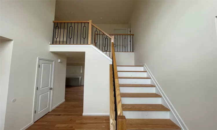 Staircase featuring hardwood / wood-style floors and a towering ceiling