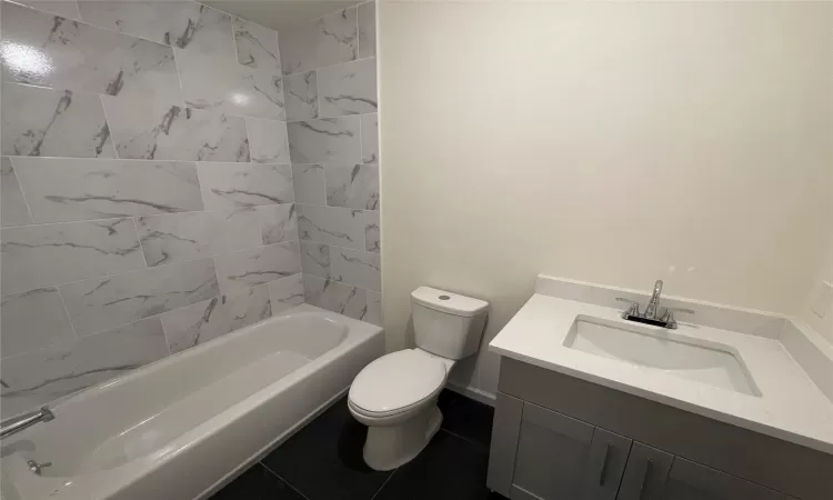 Full bathroom featuring tile patterned floors, vanity, toilet, and tiled shower / bath combo