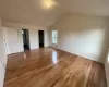 Unfurnished bedroom featuring a spacious closet, light hardwood / wood-style flooring, ensuite bathroom, vaulted ceiling, and a closet