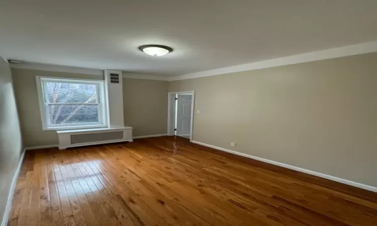 Spare room with hardwood / wood-style floors and radiator heating unit