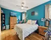 Bedroom featuring hardwood / wood-style floors, ceiling fan, and a baseboard heating unit