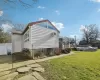 Back of house with a lawn, a wooden deck, a wall mounted air conditioner, and solar panels