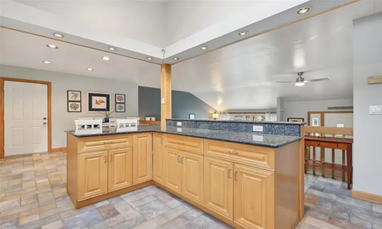 Kitchen with sink, dark stone counters, vaulted ceiling, decorative backsplash, and appliances with stainless steel finishes