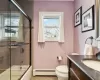 Full bathroom featuring vanity, a baseboard heating unit, bath / shower combo with glass door, tile patterned flooring, and toilet