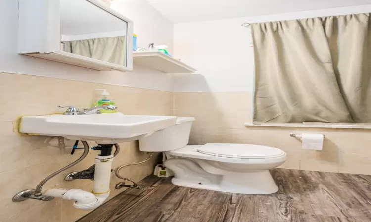 Bathroom featuring toilet, wood-type flooring, and tile walls