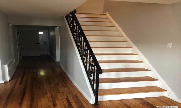 Staircase with wood-type flooring and radiator