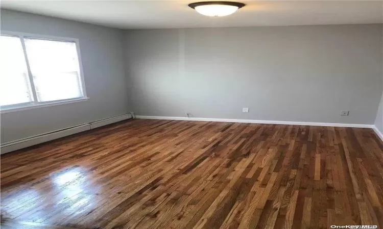 Empty room featuring dark hardwood / wood-style floors and baseboard heating