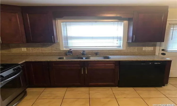 Kitchen featuring range, sink, light tile patterned floors, and black dishwasher