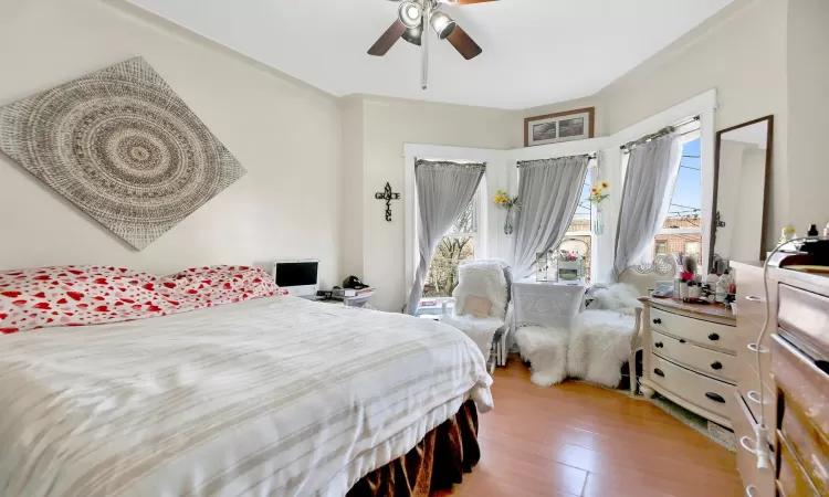 Bedroom with wood-type flooring, ceiling fan, and crown molding