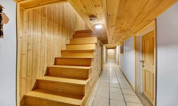 Stairs featuring tile patterned flooring, wooden ceiling, and wood walls