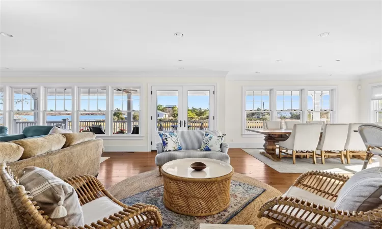 Living room featuring french doors, a water view, a wealth of natural light, and dark wood-type flooring