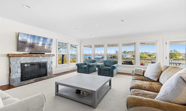 Living room with a healthy amount of sunlight, crown molding, and a fireplace