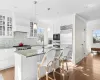 Kitchen featuring dark stone counters, a center island with sink, white cabinets, built in appliances, and plenty of natural light