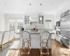 Kitchen with white cabinets, built in appliances, decorative light fixtures, and an island with sink