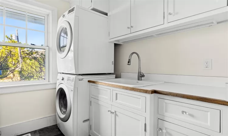 Washroom featuring cabinets, stacked washer and clothes dryer, and sink