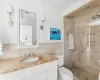 Bathroom featuring vanity, a shower with door, crown molding, toilet, and tile walls