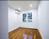 Spare room with an AC wall unit, dark wood-type flooring, a baseboard radiator, and ornamental molding