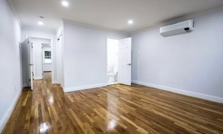 Spare room featuring dark hardwood / wood-style floors, a wall mounted AC, and ornamental molding