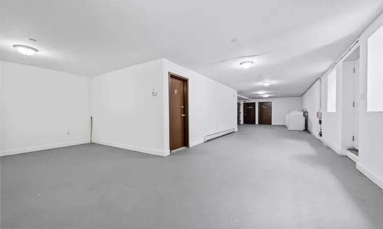 Empty room with baseboard heating, concrete flooring, and washer / dryer