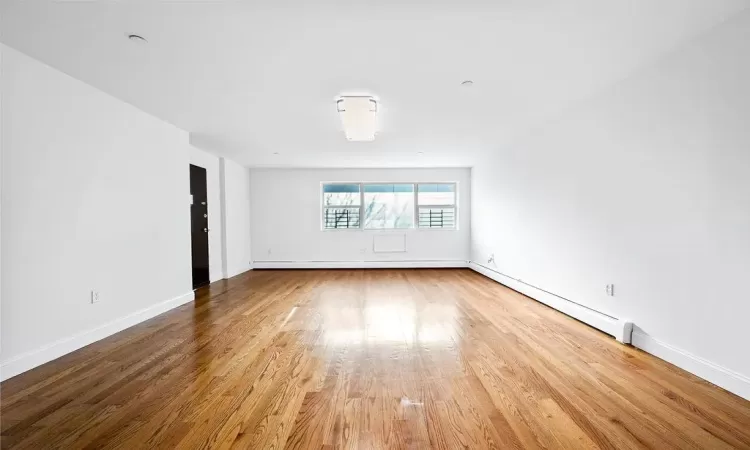 Unfurnished room with wood-type flooring and baseboard heating