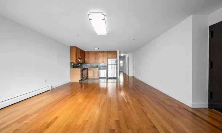 Unfurnished living room with light hardwood / wood-style floors and baseboard heating