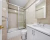 Full bathroom with bath / shower combo with glass door, vanity, tile walls, tile patterned flooring, and toilet