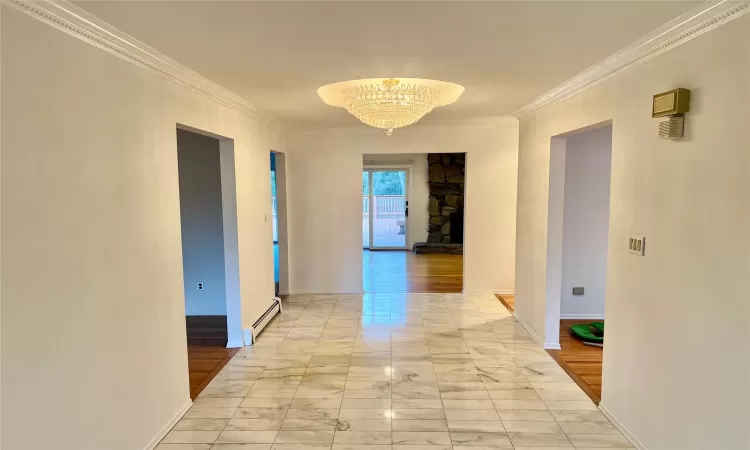 Corridor with crown molding, a baseboard heating unit, and a notable chandelier