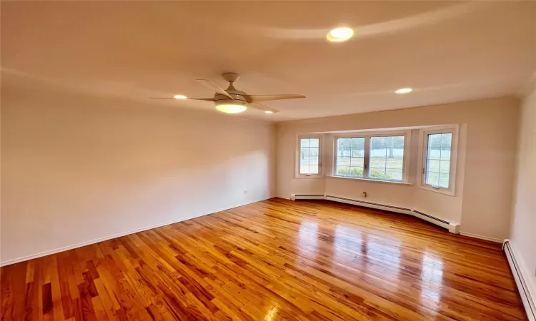 Empty room featuring ceiling fan, light wood-type flooring, and a baseboard heating unit